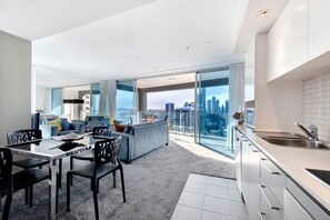 A modern apartment with a dining area, a sofa, and a kitchen with a city view. - 2 Bedroom Apartment Close To The Beach (Surfers Paradise)