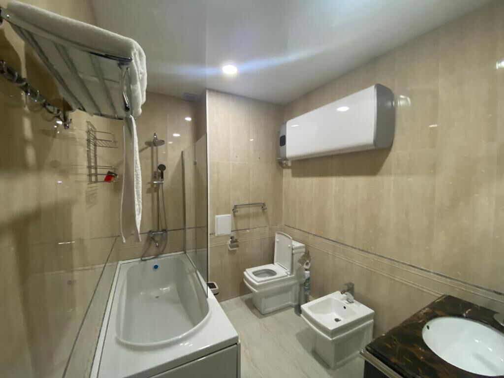 A modern bathroom with a bathtub, toilet, bidet, and sink.