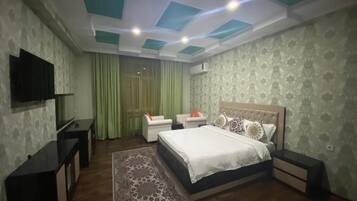 A bedroom with a bed, bedside tables, a TV, and a patterned rug.