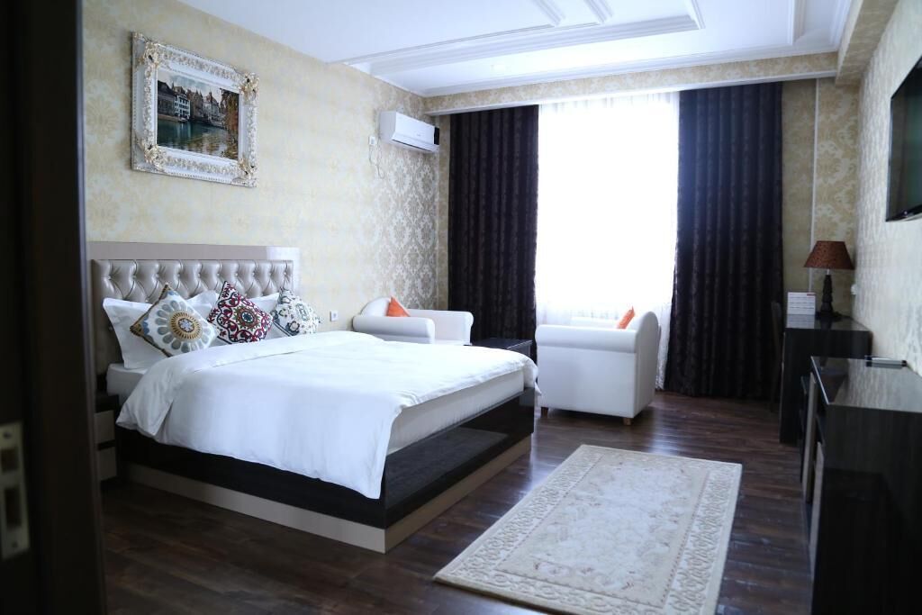 Una camera d'albergo moderna con un letto grande, un'area salotto e una televisione.