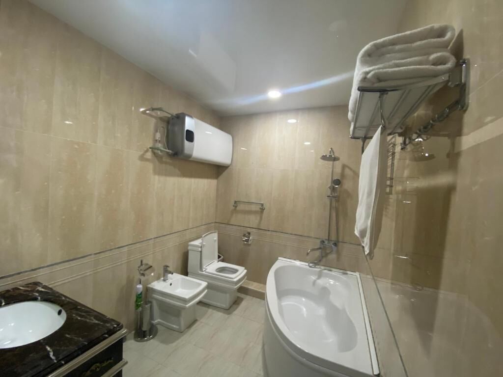 A modern bathroom with a sink, toilet, bidet, and bathtub.