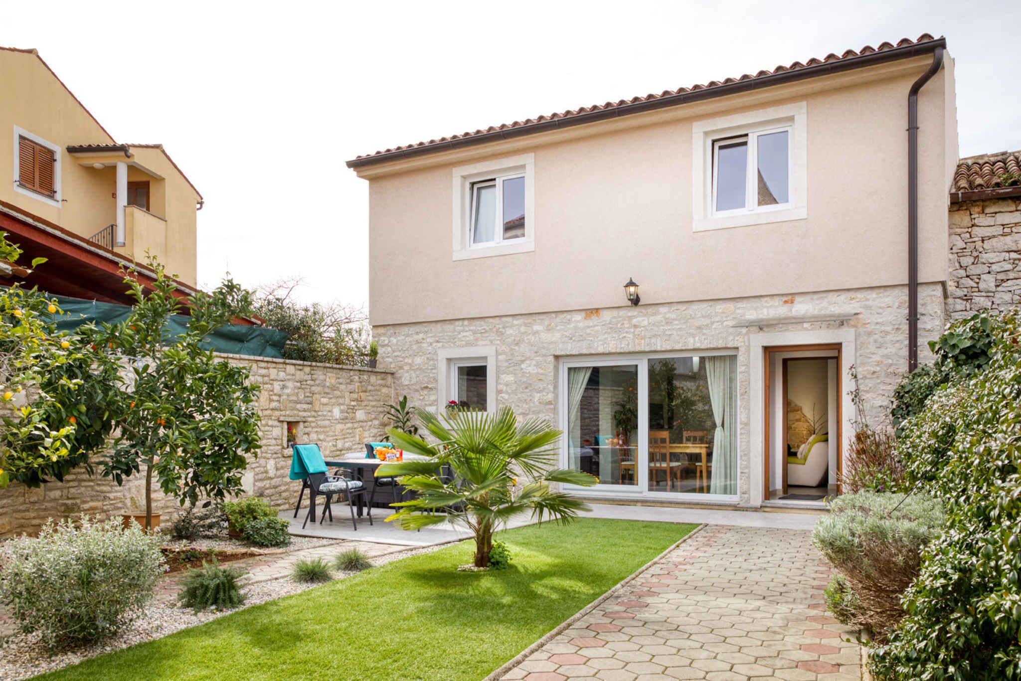 A two-story house with a stone facade, a patio with a table and chairs, and a small palm tree.