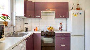 A modern kitchen with purple cabinets, a white refrigerator, a stove, and a dishwasher. - Holiday home with air conditioning (Peroj)