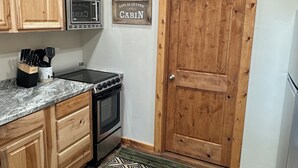 Une cuisine avec des meubles en bois, un four à micro-ondes, un four traditionnel et un tapis décoré avec des motifs d’ours.