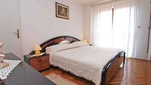 Une chambre à coucher avec un lit, des tables de chevet, une commode, une lampe, un tableau au mur et une porte.
