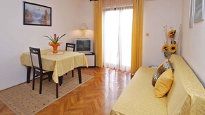 Un salon confortable avec un canapé, une table à manger et des chaises, un téléviseur et un tableau accroché au mur.