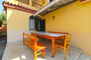 A dining area with a wooden table and benches, a tiled floor, and a yellow wall. - Holiday apartment with barbecue (Pješćana Uvala)