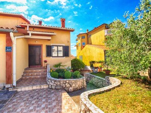 A two-story building with a stone pathway leading to the entrance. - Holiday apartment with barbecue (Pješćana Uvala)