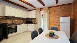 Una cocina moderna con armarios blancos, horno empotrado y comedor con mesa y sillas.