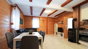 Un interior de madera con una mesa de comedor, sillas, un sofá, un televisor y una zona de cocina con estufa.