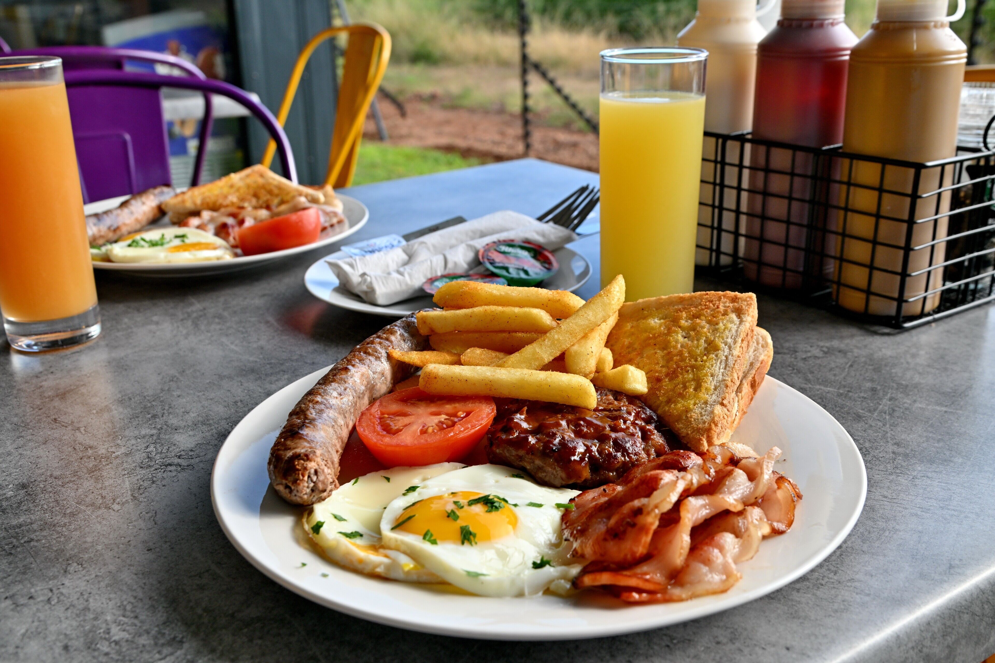 A breakfast plate with eggs, bacon, sausages, toast, and fries.