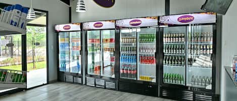 Interior de una tienda con varios mostradores refrigerados con etiquetas que dicen 'Sleepover' y llenos de bebidas.