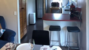 A compact kitchen with a refrigerator, microwave, and a small dining area with a table set for two.