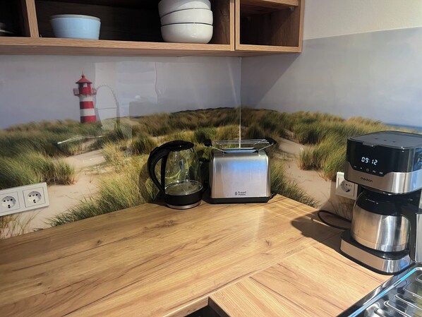 A kitchen counter with a coffee maker, a kettle, and a toaster.