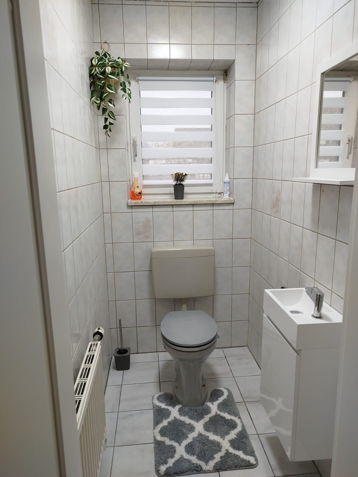 Een kleine badkamer met toilet, wastafel en raam.