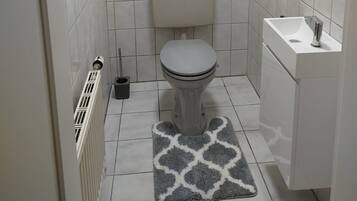 Een kleine badkamer met toilet, wastafel en raam.
