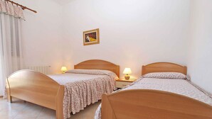 Een slaapkamer met twee houten bedden, een radiator, een lamp en een lijst met een afbeelding aan de muur.