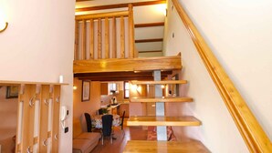 A wooden staircase leading to a second floor with a dining area below.