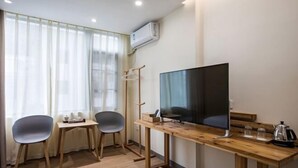 A room with a wooden desk, two chairs, a television, and a window with sheer curtains. - Wuyishan Yunzhong Jinshu Homestay (Wuyishan)