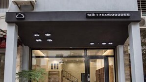 A modern building entrance with a glass door, a contact number, and a cloud symbol. - Wuyishan Yunzhong Jinshu Homestay (Wuyishan)
