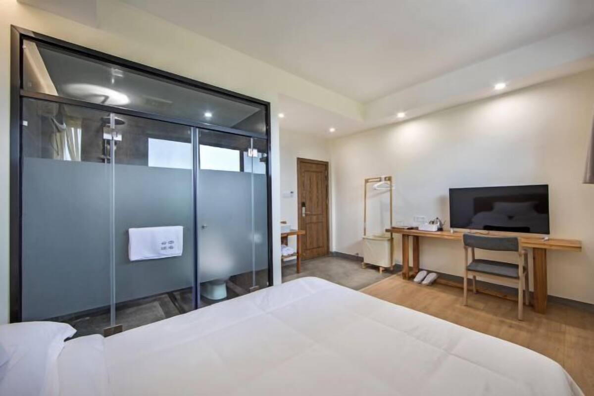 Ein Hotelzimmer mit Bett, Schreibtisch mit Stuhl, Fernseher und Kleiderschrank.