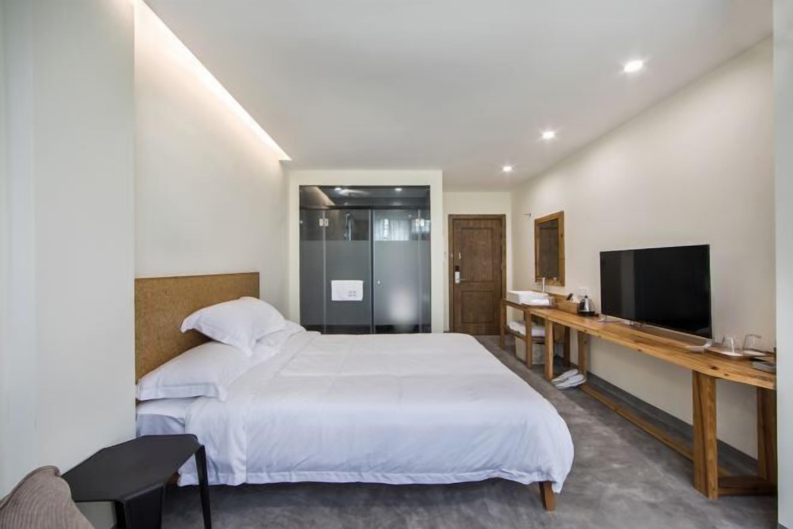 Une chambre d’hôtel comprenant un lit, un bureau avec une télévision, un miroir et une porte donnant accès à une salle de bain.