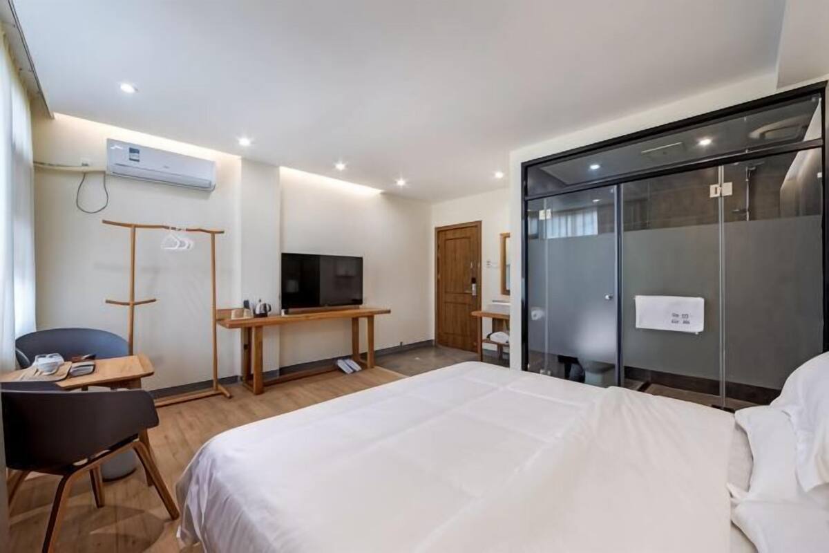 Ein Hotelzimmer mit Bett, Schreibtisch mit Fernseher, Stuhl, Kleiderschrank und Duschbereich.