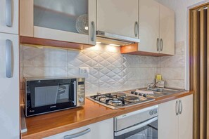 Une cuisine équipée d’un four à micro-ondes, d’une cuisinière, d’un four et de placards.
