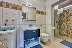 Ein Badezimmer mit Dusche, Toilette, Waschbecken und Spiegel.
