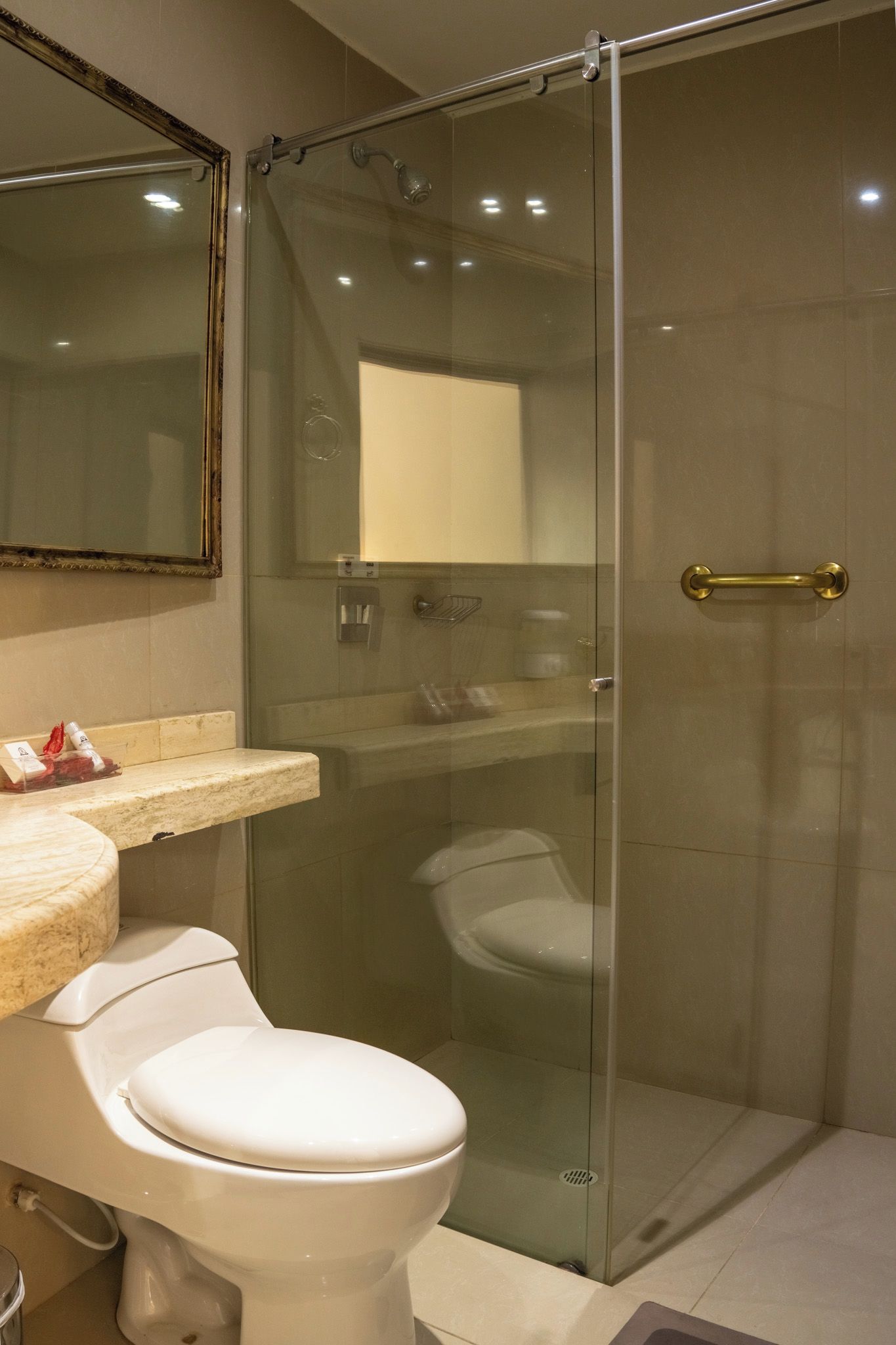 Un baño moderno con cabina de ducha de vidrio, inodoro y tocador con espejo.