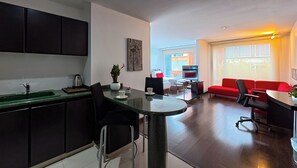 Eine moderne Küche mit Essbereich, einem roten Sofa und Blick ins Freie.