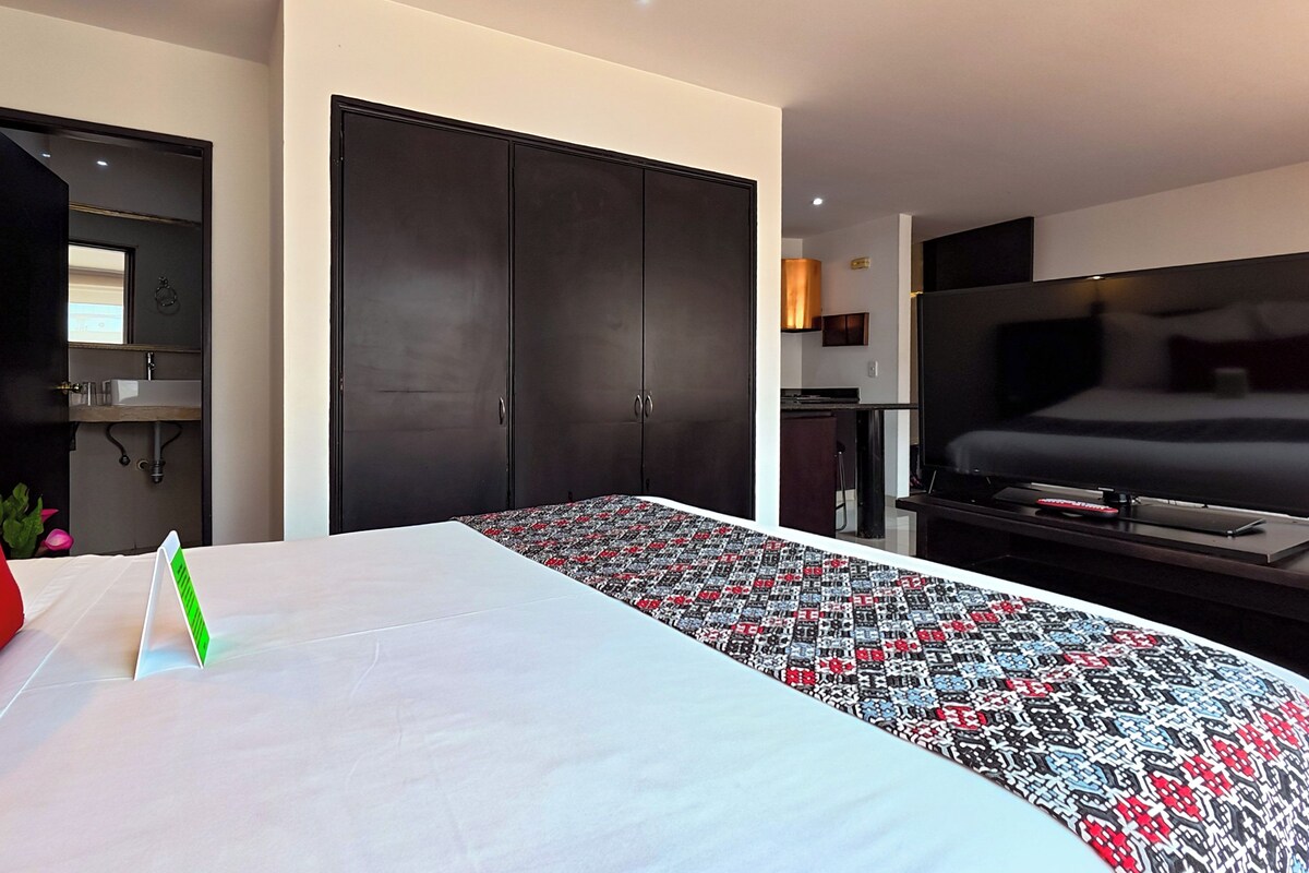 Een hotelkamer met een bed, een televisie, een kledingkast en een badkamer, zichtbaar door een geopende deur.
