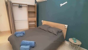 A bedroom with a bed, two pillows, a small round table with a ball, and a wardrobe with a mirror.