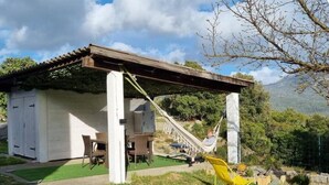 A white building with a covered patio, a hammock, and a yellow chair.