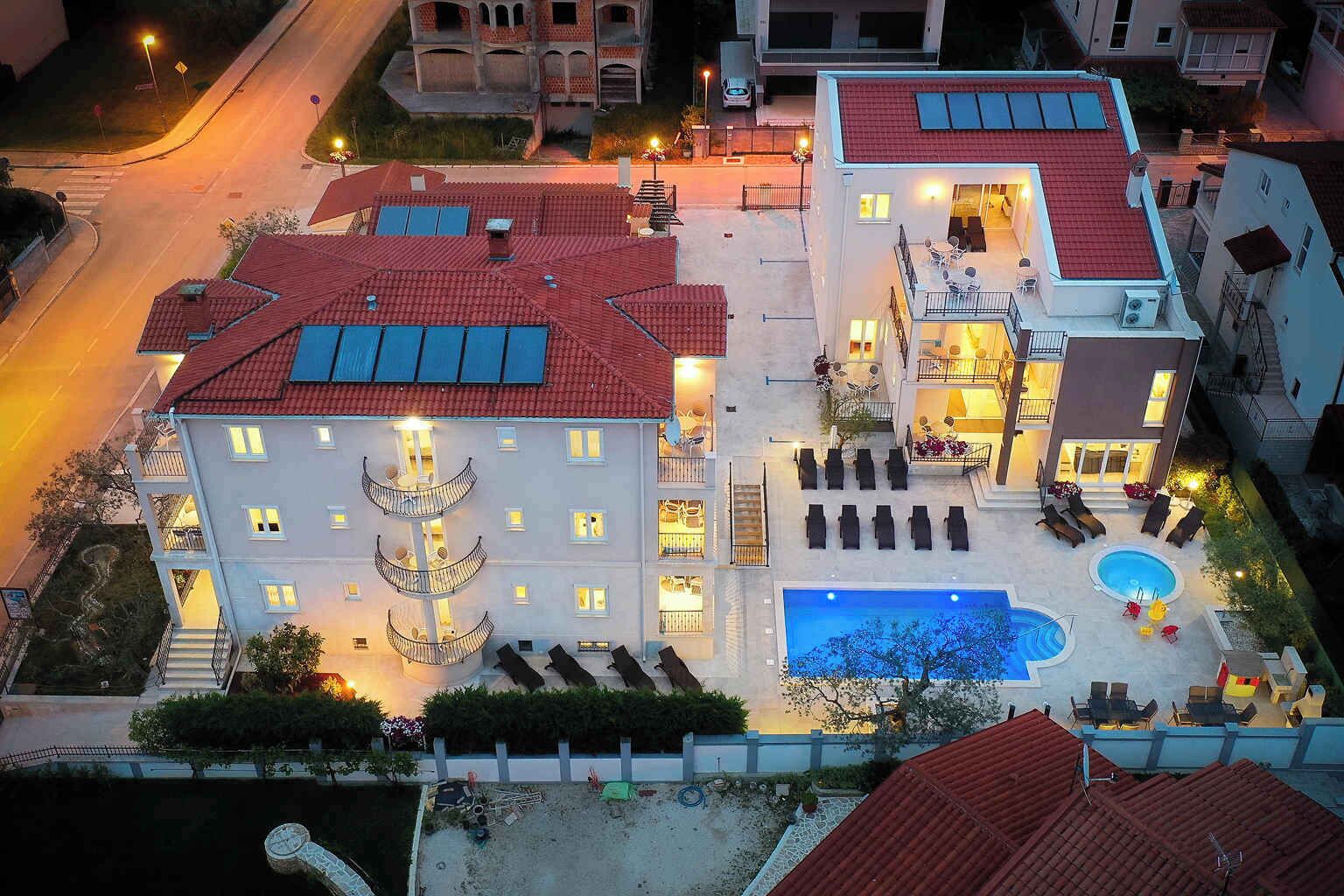 Ein mehrstöckiges Hotel mit Pool auf dem Dach, Außenbereich zum Sitzen und einem gut beleuchteten Innenhof.