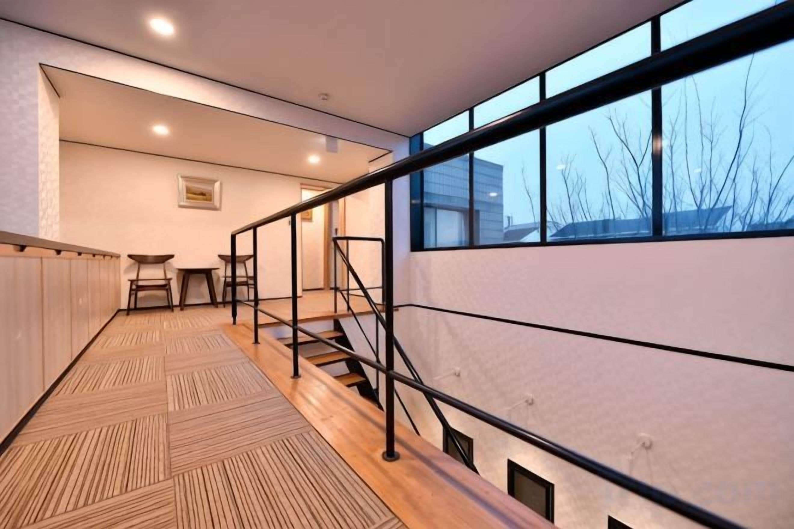 A modern interior with a staircase, wooden flooring, and large windows.
