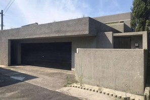 A building with a garage, a concrete wall, and a paved driveway. - BRUCE HOUSE (Izumisano)