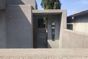 Ein Betonaufgang mit einem Metallgitter, einem kleinen Schild und einem Bedientableau.