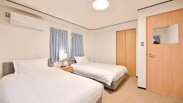 A hotel room with two beds, a wooden door, and a mirror.