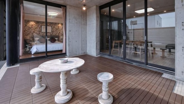 A modern interior with a round marble table, a bedroom with a bed and a large window, and a dining area with tables and chairs. - BRUCE HOUSE (Izumisano)