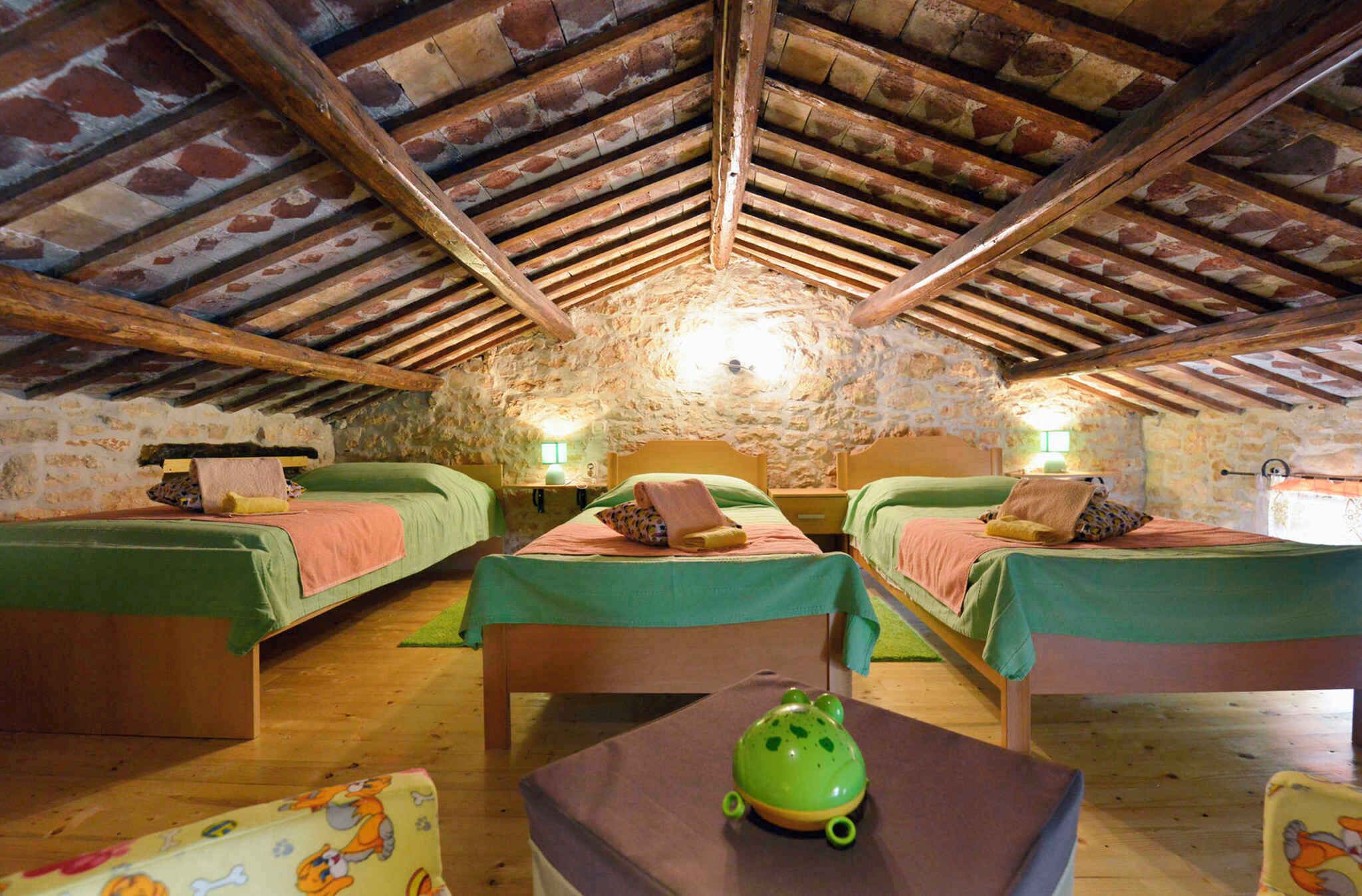 Une pièce rustique avec trois lits, des poutres en bois, des murs en pierre et un objet en forme de grenouille verte posé sur une table.