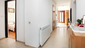 Un couloir avec un radiateur, une porte en bois et une petite table sur laquelle se trouvent un panier et une plante.