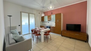 A modern apartment with a dining area, a sofa, a TV, and a kitchen. - Bavierino in Cattolica (Cattolica)