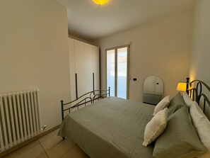 A bedroom with a bed, a radiator, a mirror, and a window. - Bavierino in Cattolica (Cattolica)