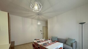 A dining area with a white table set for four, red chairs, and two pendant lights. - Bavierino in Cattolica (Cattolica)