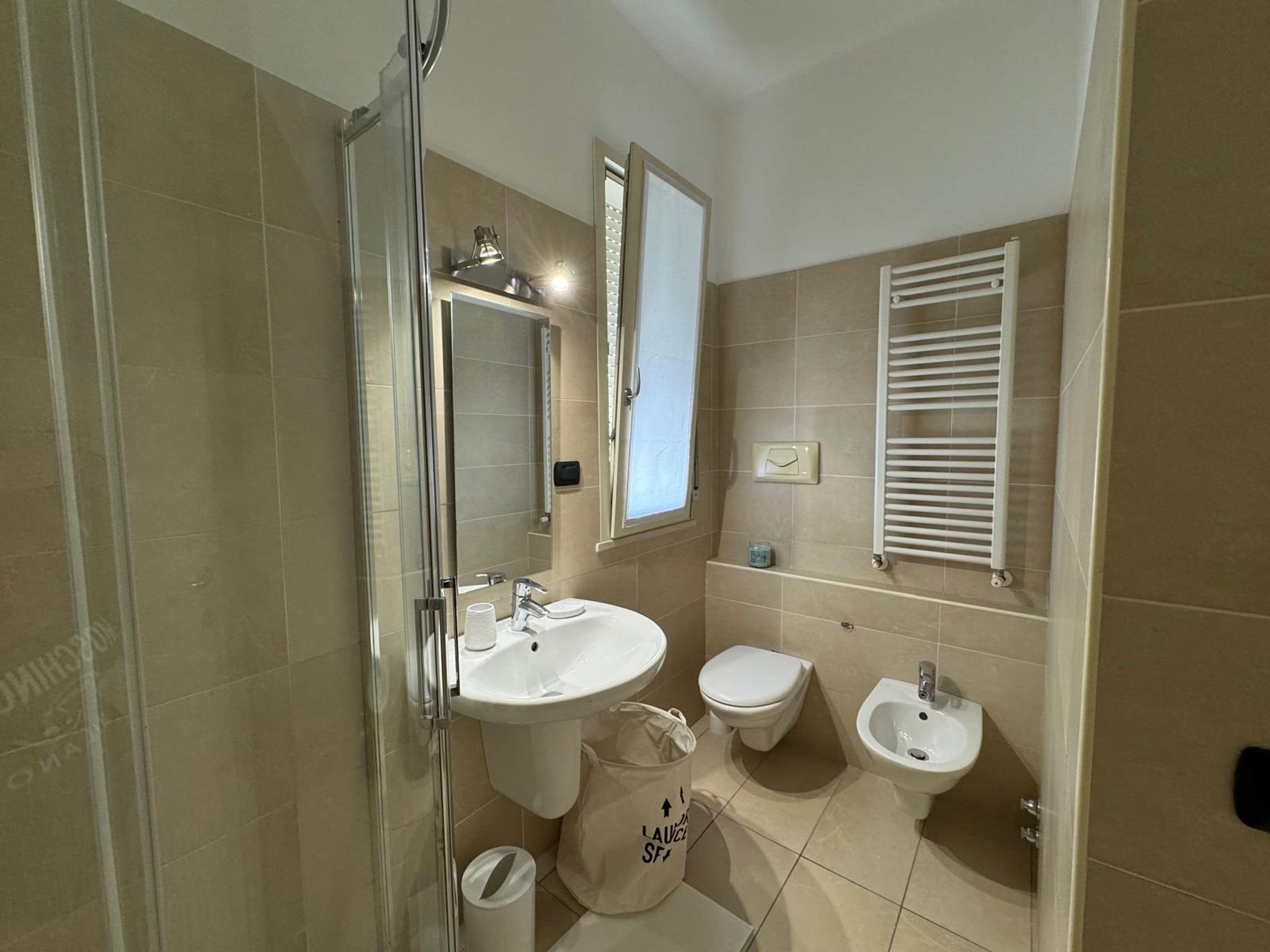 Un bagno con box doccia in vetro, lavandino, WC e bidet.