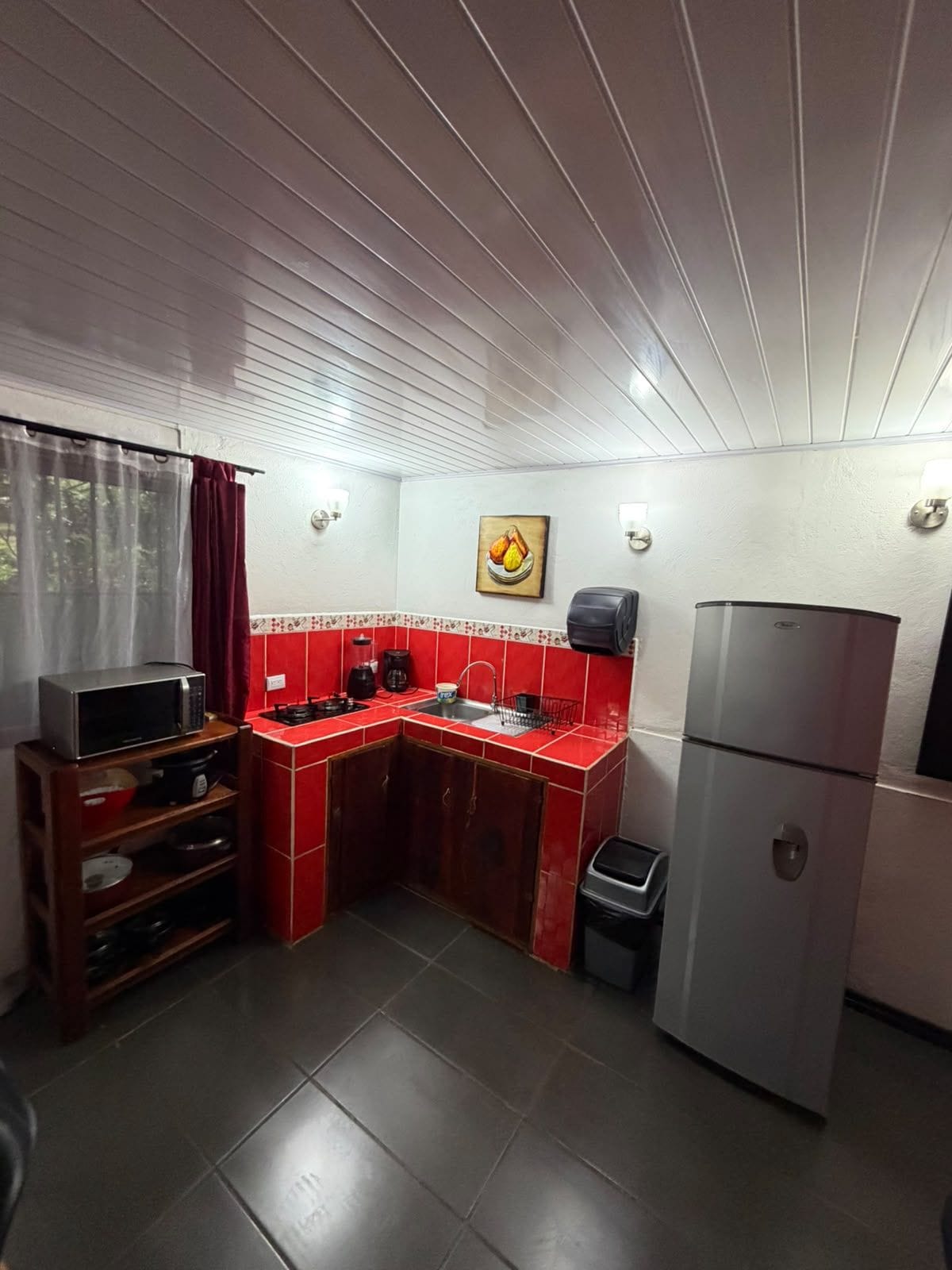A compact kitchen with a microwave, coffee maker, and a refrigerator.
