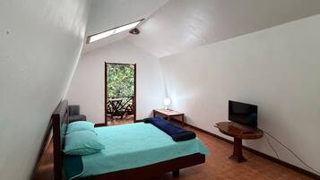 Une chambre à coucher avec un lit, une table de chevet, une lampe et un téléviseur posé sur un meuble.