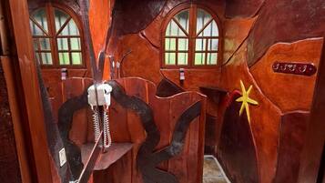 Un baño con diseño rústico, que cuenta con techo de madera, tragaluz, lavamanos, inodoro y una pared decorativa con una estrella.