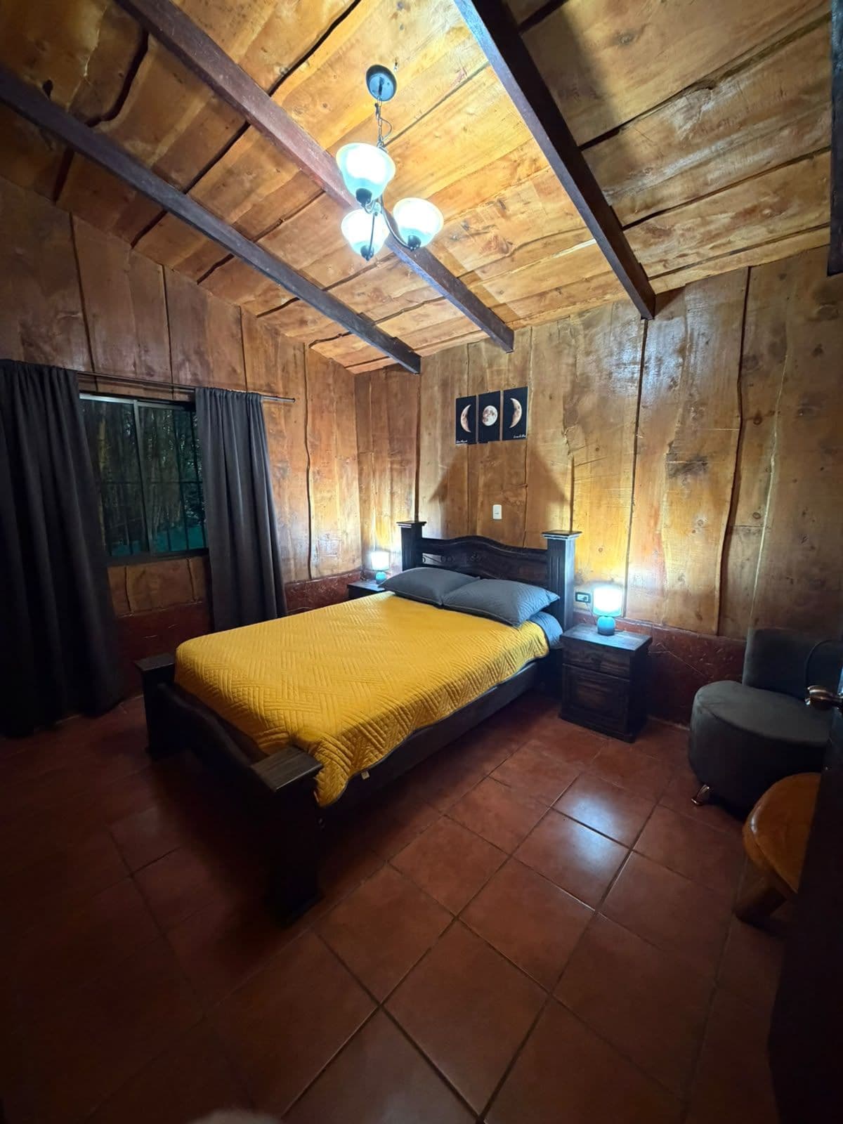 A wooden room with a bed, nightstands, and a chair.